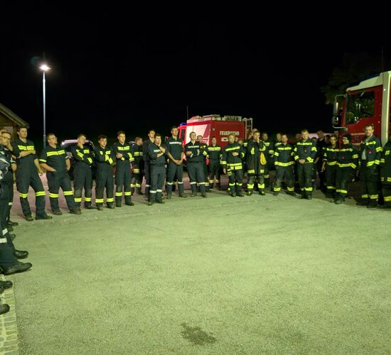 Die Teilnehmenden der Übung stehen im Kreis vor dem Feuerwehrhaus