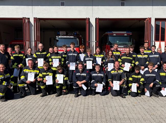 Die Absolventen der Basisausbildung stehen lächelnd mit Urkunden vor dem Feuerwehrhaus in Böheimkirchen.