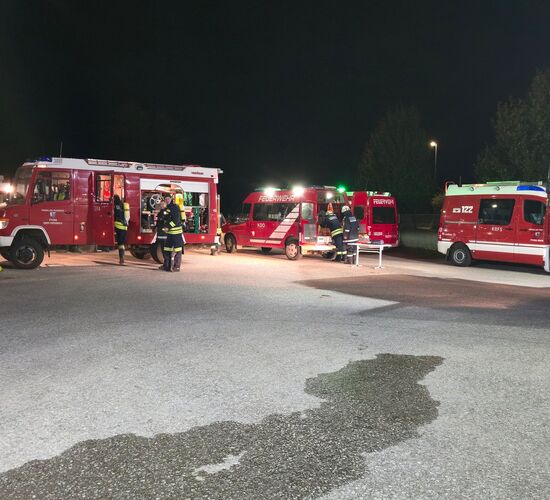 Feuerwehrmitglieder rüsten sich mit Gerätschaft aus den Fahrzeugen aus