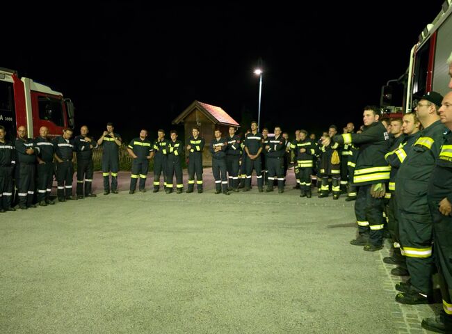 69 Feuerwehrmitglieder stehen bei der Nachbesprechung im Kreis