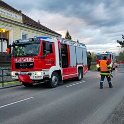 Ein Feuerwehrwagen steht an einer Straße vor einer Schule, während ein Einsatzleiter Anweisungen gibt.